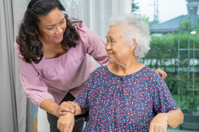 Help Asian older woman sitting on wheelchair is being tended to by a younger woman