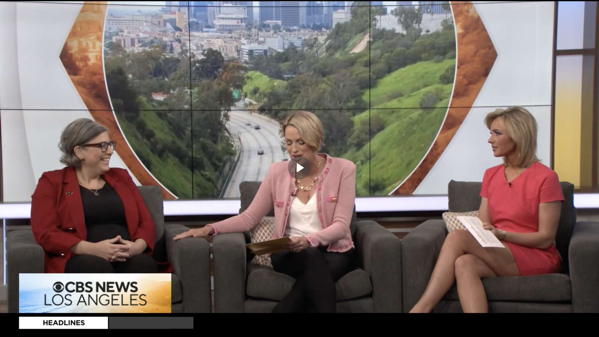 Three women sit in sofa chairs having a discussion on a news set.