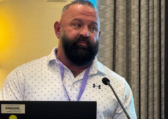 A man with a beard gives a presentation in front of a microphone