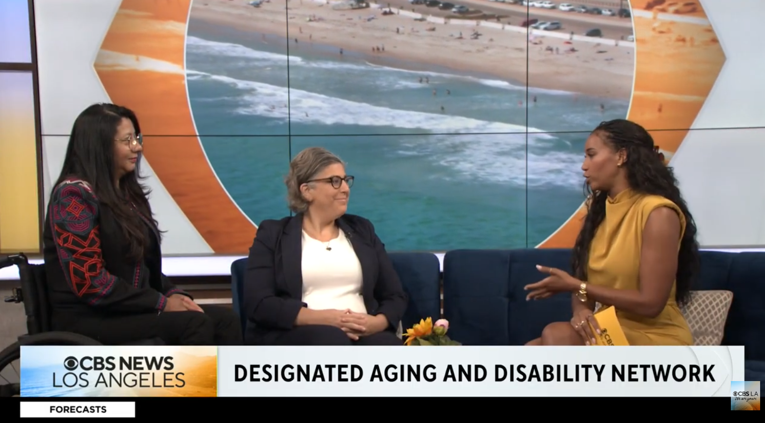 Three women sit on a stage on a news program.